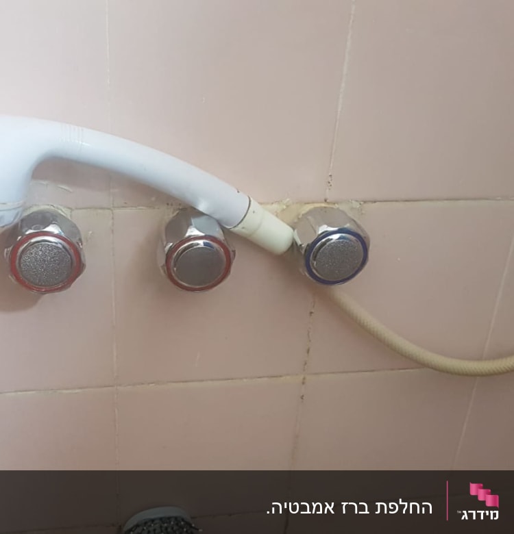 ראש מקלחת לבן עם ברזים על קיר קרמיקה